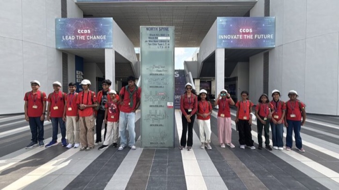 A group of students in red T-shirts and white helmets posing at an innovation centre