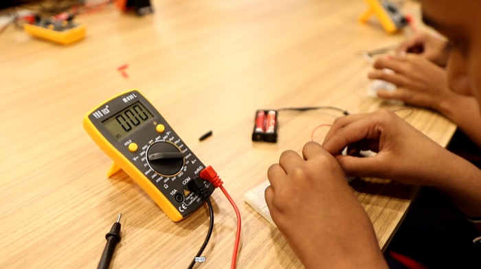 Student measuring a circuit with a multimeter